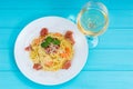 High angle view of appetizing spaghetti pasta in white plate near glass with wine on blue wooden table Royalty Free Stock Photo