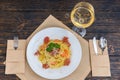 High angle view of appetizing spaghetti pasta in white plate near glass with wine on decorated table with linen napkin Royalty Free Stock Photo