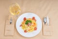 High angle view of appetizing spaghetti in white plate near glass with wine on decorated table with light tablecloth Royalty Free Stock Photo