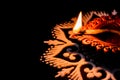 High angle view of awesome burning diya and white rangoli art on black background with copy space in left. diwali concept Royalty Free Stock Photo