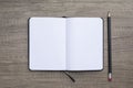 High angle view of blank opened note pad and black pencil on wooden background.