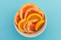 High angle view of bowl of freshly cut orange slices on blue background