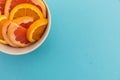 High angle view of bowl of freshly cut orange slices on blue background