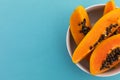 High angle view of bowl of freshly cut papaya on blue background