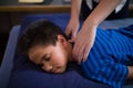 High angle view of boy sleeping on bed while receiving back massage from female therapist