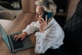 High-angle view of busy businesswoman talking phone typing laptop multitask in office. Portrait of busy female