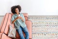 High angle view at calm young woman in casual wear with smartphone laying on the couch in cozy living room Royalty Free Stock Photo