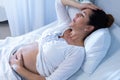 Pregnant woman suffering from pain while touching her belly in the ward Royalty Free Stock Photo