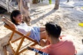 High angle view of caucasian young couple talking while sitting on deck chairs at beach Royalty Free Stock Photo