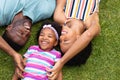 High angle view of cheerful african american parents lying with daughter on grass at garden Royalty Free Stock Photo