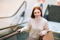 High-angle view of cheerful pretty young woman holding on escalator handrail and riding escalator going up in shopping Royalty Free Stock Photo
