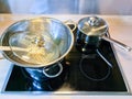 High angle view of a chrome pasta strainer in a pot on a stove