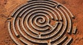 High-angle view of a circular stone labyrinth pattern on dry, cracked orange desert ground at sunset Royalty Free Stock Photo