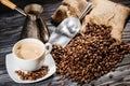 high angle view of coffee cup with scoop and cezve on heap of coffee beans and on rustic