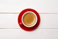 High angle view of coffee in red cup with saucer on white wooden background, close up Royalty Free Stock Photo