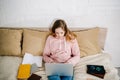 High angle view of concentrated teenager kid lying on bed with books and using laptop.