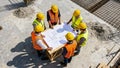 High-angle view of a construction team discussing architectural blueprints on site. Royalty Free Stock Photo