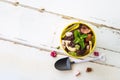 High angle view a cookie crumbs in a yellow pot decorated with worm jelly, chocolate gravel and pepermint with toy shovel on white