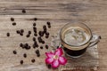 High-angle view of a cup of black americano coffee on a sackcloth rustic wooden table with a flower and a pile of organic brown