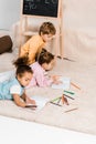 high angle view of cute multiethnic children lying on carpet and