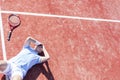 High angle view of disappointed mature man with head in hands while lying by tennis racket on court during summer Royalty Free Stock Photo