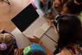 High angle view of diverse female teacher and girls looking at laptop while studying online on table Royalty Free Stock Photo