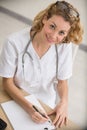 high-angle view doctor sat at desk writing on clipboard Royalty Free Stock Photo