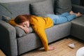 High-angle view of exhausted pretty woman sleeping on cozy couch in living room, lying on stomach. Tired young female Royalty Free Stock Photo