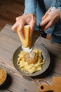 High angle view of female hands grating cheese into pasta