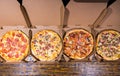 High angle view of four pizzas with variety of toppings and cheese in cardboard take out boxes Royalty Free Stock Photo