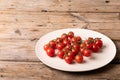 High angle view of fresh red cherry tomatoes in plate on brown wooden table Royalty Free Stock Photo