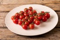 High angle view of fresh red cherry tomatoes in white plate on wooden table Royalty Free Stock Photo