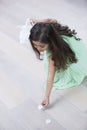 High angle view of girl picking up flower petals from floor at home