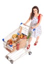 High angle view of girl smiling at camera while pushing a shopping cart full with groceries isolated on white background Royalty Free Stock Photo