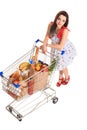 High angle view of girl smiling at camera while pushing a shopping cart full with groceries isolated on white background Royalty Free Stock Photo
