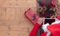 High angle view of the hands of a senior woman wearing a Santa`s hat using technology with a small tablet. Wooden table decorated