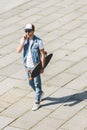 high angle view of handsome young skateboarder walking with longboard in hand and talking Royalty Free Stock Photo