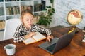 High-angle view of happy focused Caucasian school girl studying with books laptop preparing for test exam writing essay Royalty Free Stock Photo