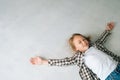 High-angle view of happy smiling little girl lying on floor, spreading arms and legs, making angel. Royalty Free Stock Photo