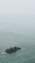 High angle view of a huge rock in the middle of the ocean on a gloomy day