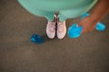 High angle view of legs of fit woman in pink athletic shoes holding blue elastic band for fitness and standing on playground next