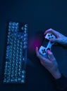 High angle view of male hands using game controller next to backlit computer keyboard Royalty Free Stock Photo