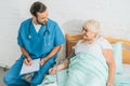 high angle view of male nurse writing on clipboard while measuring blood pressure to smiling senior woman Royalty Free Stock Photo