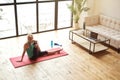 High angle view of mature woman going in for sports at home, sitting on yoga mat and stretching her body in front of Royalty Free Stock Photo