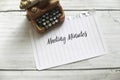 High angle view of miniature typewriter and paper written with Meeting Minutes on white wooden background