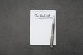 High angle view of a notepad with the to do list and a pen on grey desk Royalty Free Stock Photo