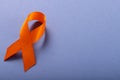 High angle view of orange leukemia awareness ribbon isolated against blue background, copy space