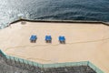 Concrete beach with tree couple of blue deck chairs under the sun light, Madeira island, Portugal