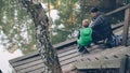 High angle view of people father and son fishing in pond in forest sitting on chairs on wooden pier and holding rods Royalty Free Stock Photo