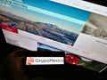 High angle view of person holding smartphone with logo of Mexican mining company Grupo MÃÂ©xico on screen in front of website.